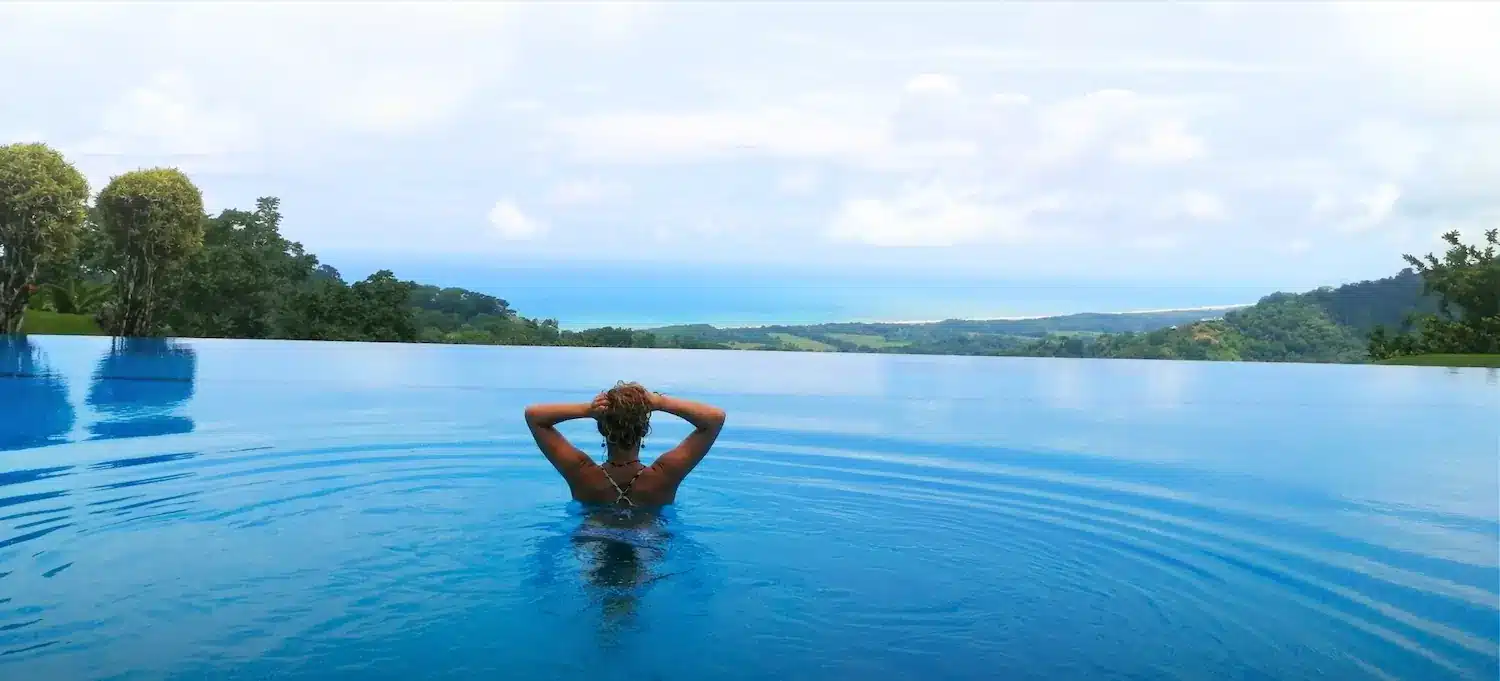 Woman relaxing on surfboard in infinity pool overlooking Pacific Ocean at Lamangata luxury villa Manuel Antonio