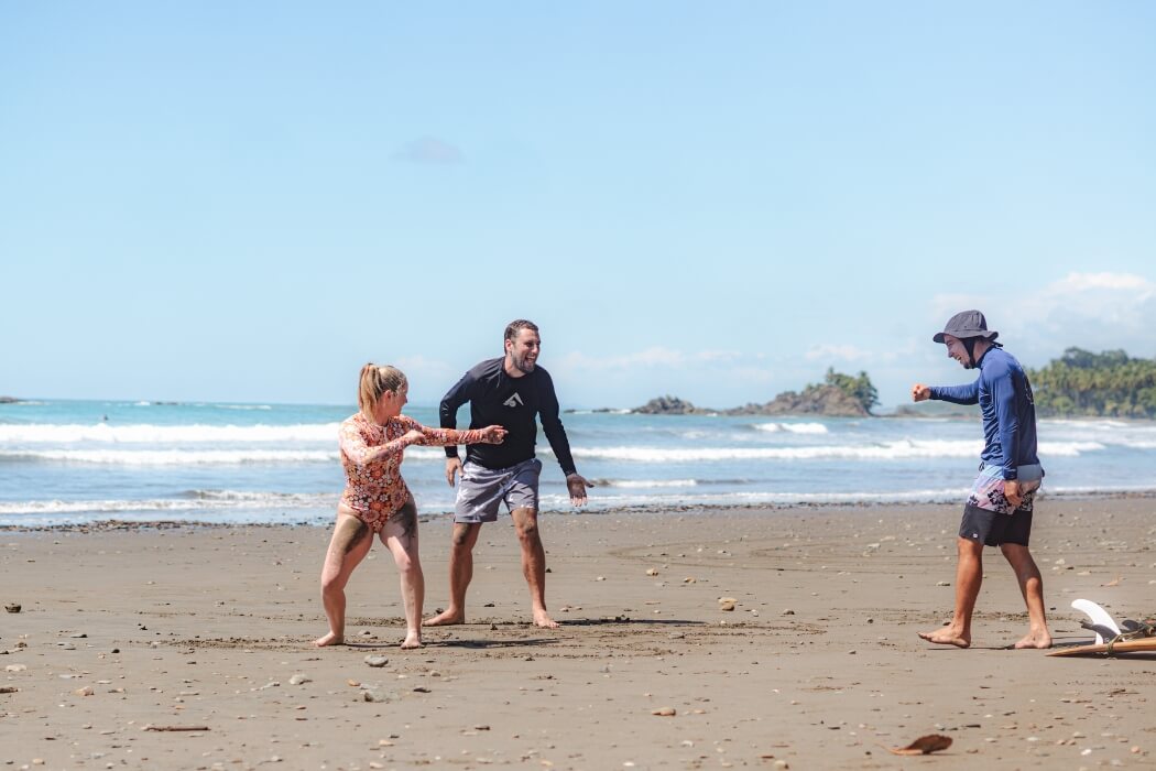 Surf instructors teaching surfing techniques on a black sand beach in Costa Rica