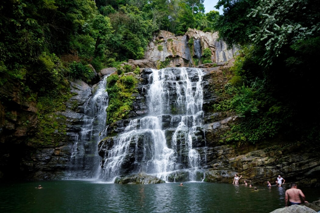 Multi-tiered Nauyaca waterfall with swimmers enjoying natural pool in Costa Rica