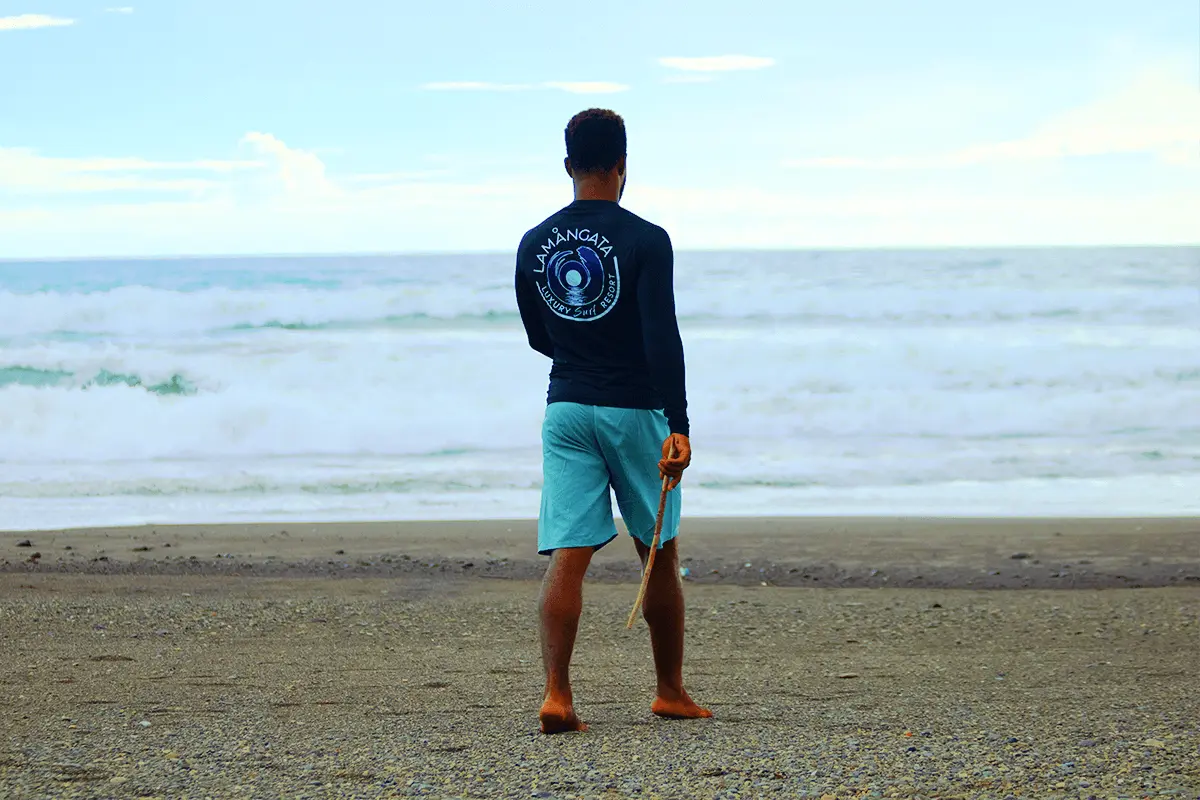 Man Looking Toward the Ocean on a Costa Rica Beach Man standing on the beach in Costa Rica, looking out at the ocean horizon with waves gently rolling in.