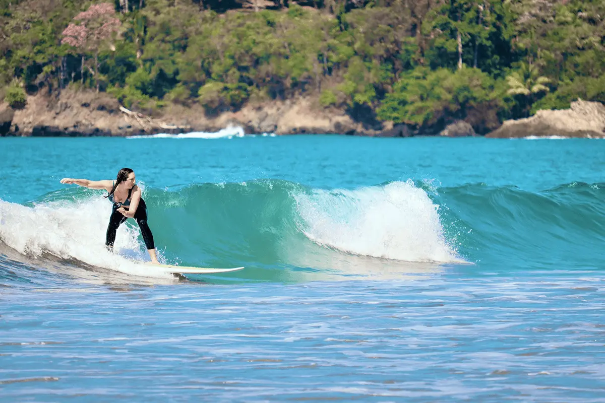 Woman Surfing at Playa Hermosa – Uvita & Dominical, Costa Rica Woman surfing a clean wave at Playa Hermosa near Uvita and Dominical, Costa Rica, with lush jungle in the background.