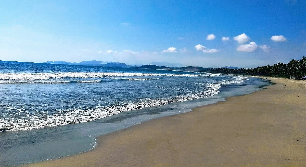 Playa Linda Shoreline with Gentle Waves Wide view of Playa Linda’s empty shoreline in Costa Rica, with gentle waves, palm trees, and a peaceful, uncrowded beach.