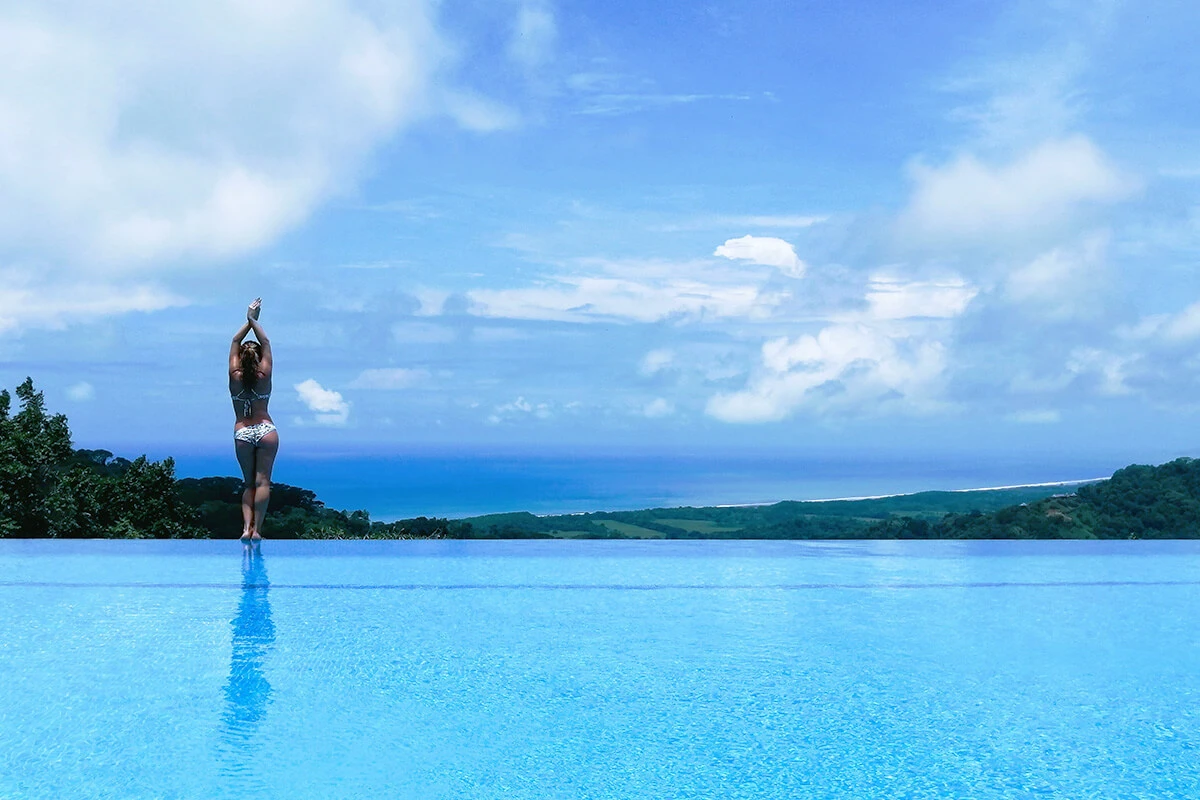 Infinity Pool Overlooking the Ocean at Lamangata Luxury Surf Resort in Costa Rica Surf coach guiding a guest through balance techniques in the infinity pool at Lamangata Surf Resort in Costa Rica.