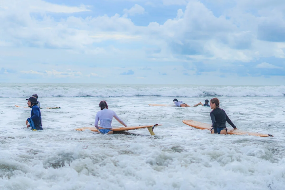Students paddling into the waves during a surf lesson in Dominical, Costa Rica.