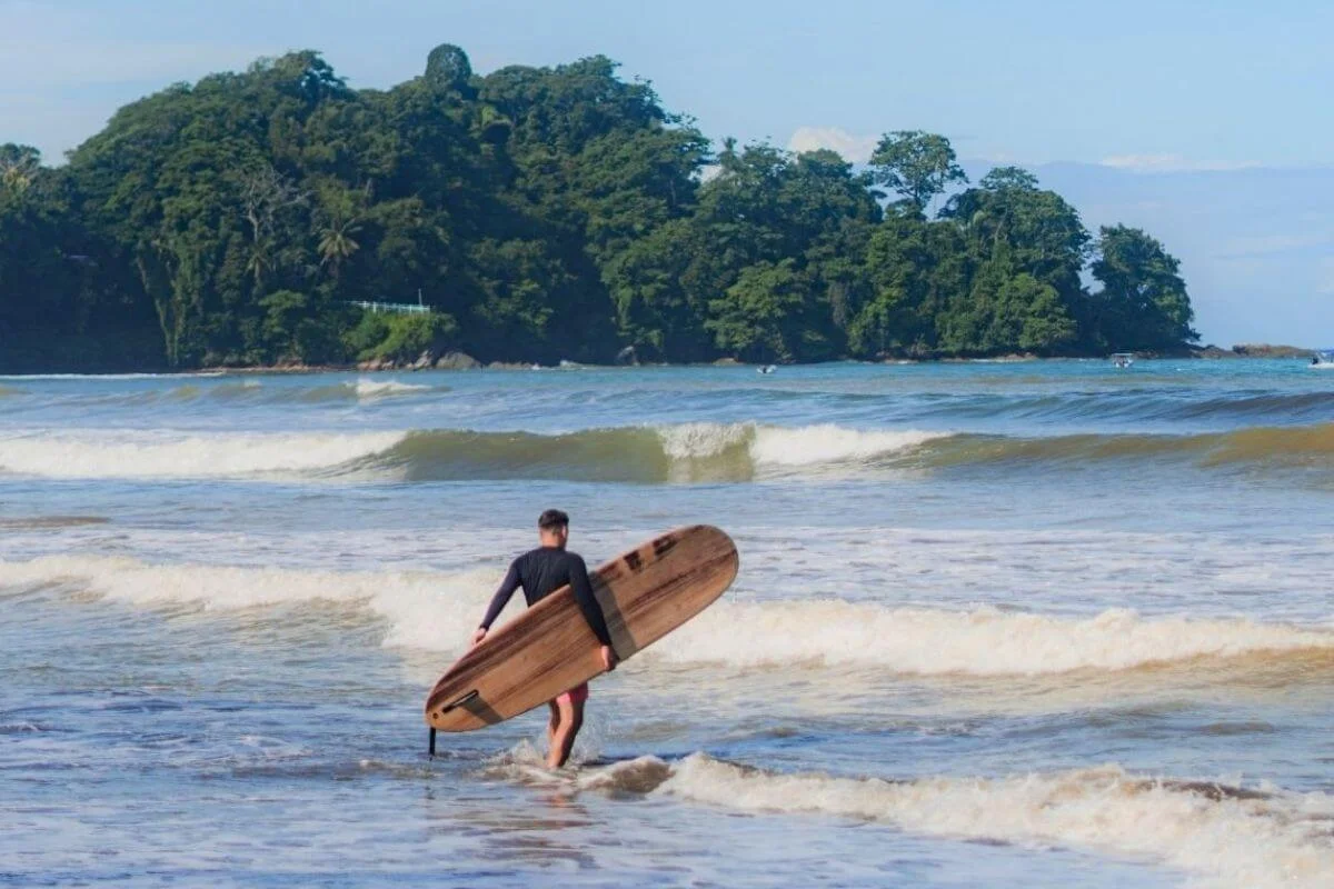 Surfer walking into ocean waves with surfboard in Costa Rica