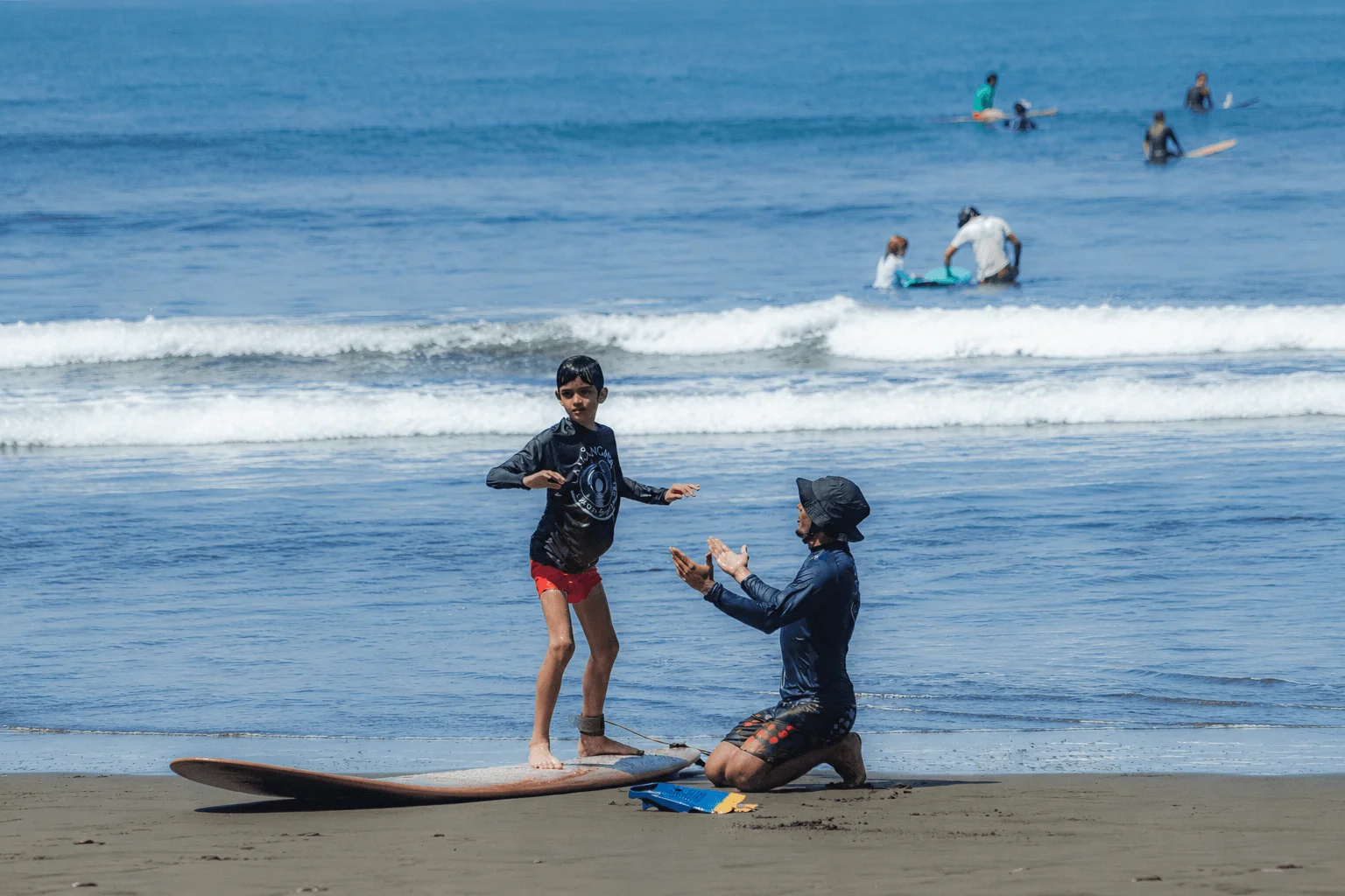 Coach Junior teaching a child to surf in Dominical, Costa Rica.
