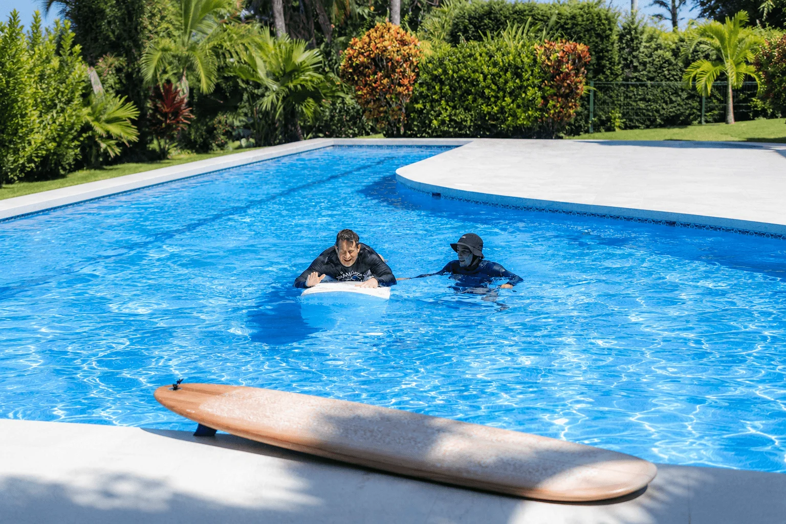 Coach guiding student through surf paddle practice in pool