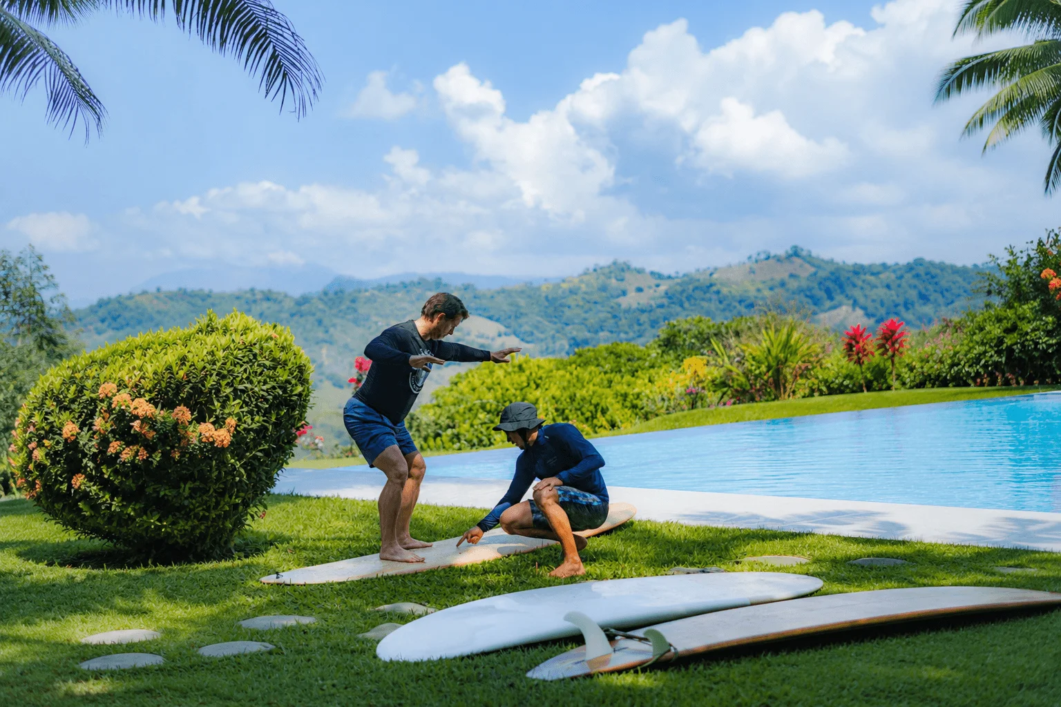 Instructor teaching surf pop up technique on surfboard by pool