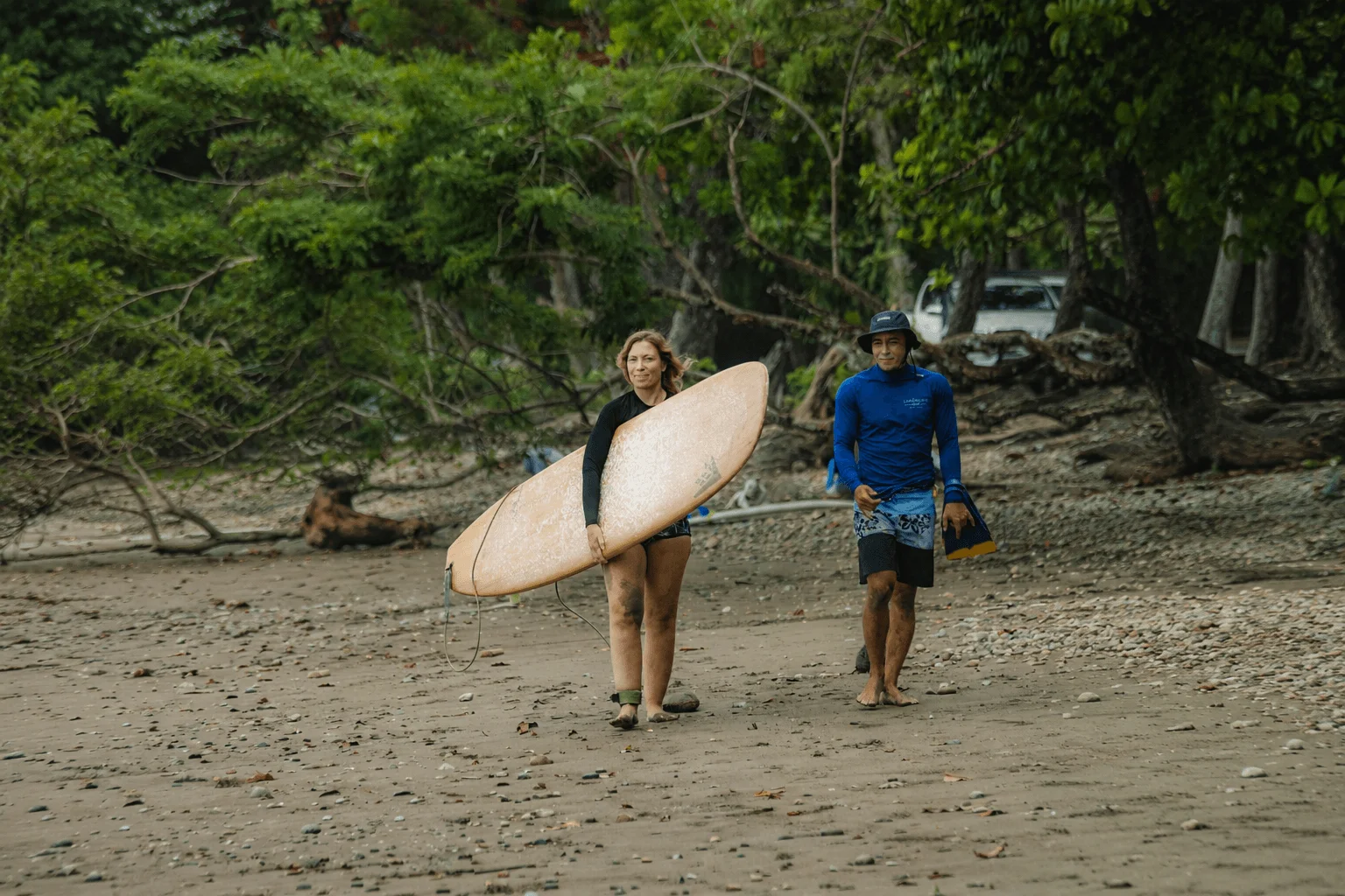 Coach Junior walking with a student to a surf lesson in Dominical, Costa Rica.