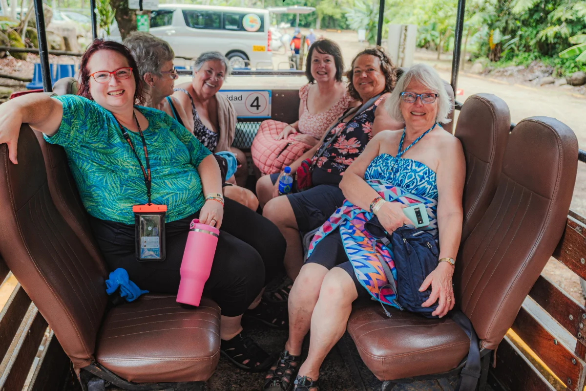Group of guests smiling and seated in an open-air trolley on the way to Nauyaca Waterfalls
