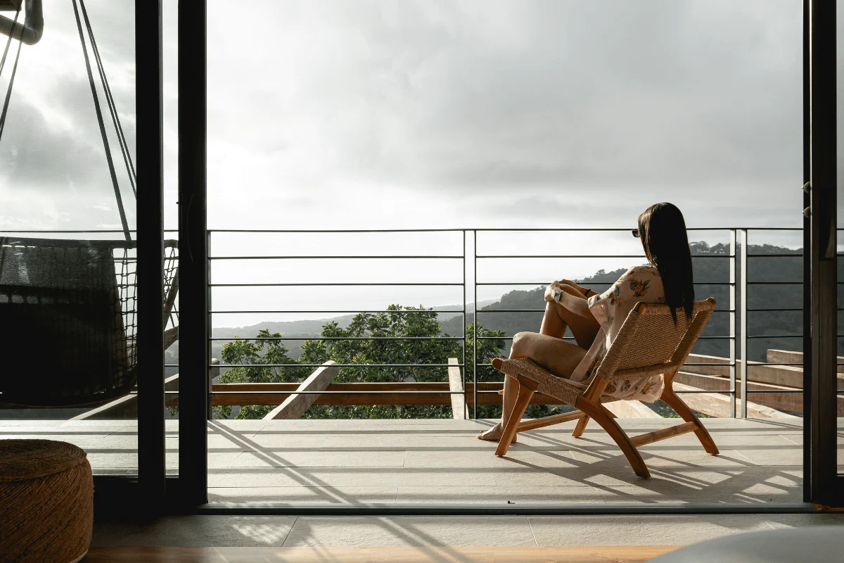 Woman relaxing on deck chair overlooking rainforest and ocean