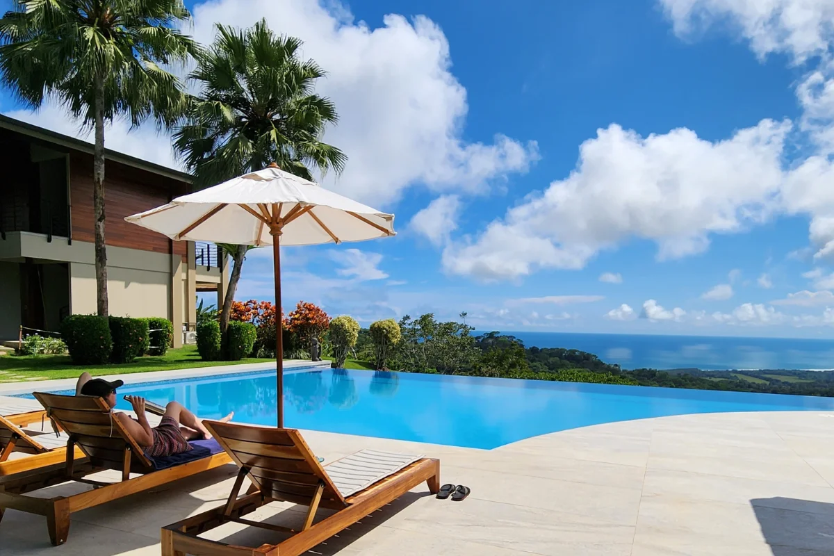 Guest relaxing on a lounge chair by an infinity pool overlooking the ocean and rainforest in Costa Rica