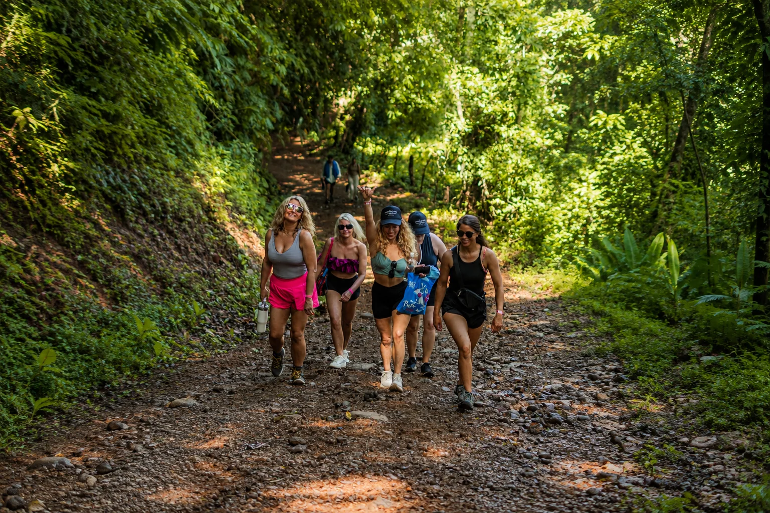 Group of friends walking down a rocky rainforest trail on the way to Nauyaca Waterfalls